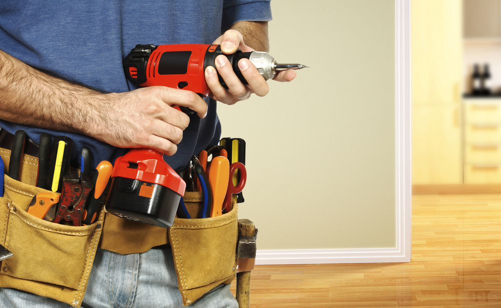 handyman with work belt on holding a power drill.